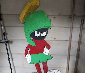 A green and red cartoon character adorns a white wooden wall