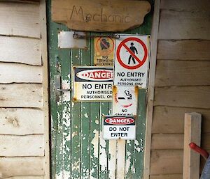 A faded green door with no entry signs on it