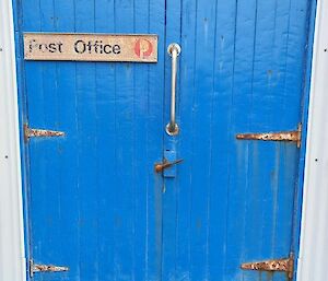 A double blue door with a post office sign on it.