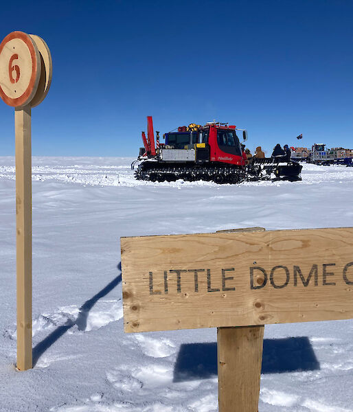 Two vehicles sit on the snow with a sign saying Little Dome C