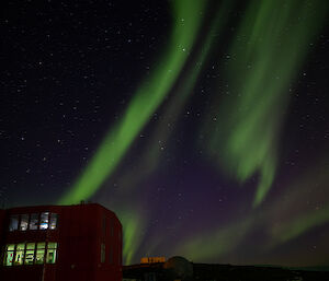 A green aurora floats over a station building