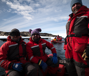 Three men wearing cold weather clothing in a boat smiling broadly