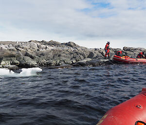 A group of people in an inflatable boat land on a rocky shore