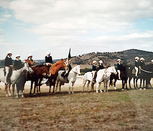 Eleven horses and their riders in a line