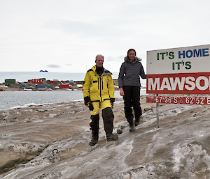 Two men and a woman next to a sign with station and ice plateau in the background