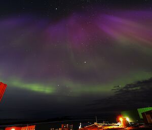 Aurora in the night sky with station buildings below