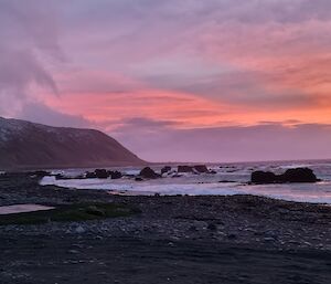 A pink sunset is on show over the coast of an island