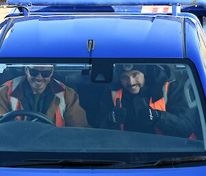 Two smiling men give thumbs up through the ute windscreen.