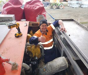 A man working on machinery giving the thumbs up