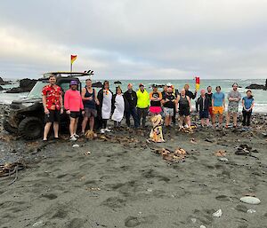 A group of people lined up on a beach for the mid winter swim