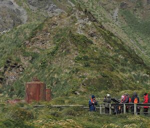 People looking at old, rusty oil tanks