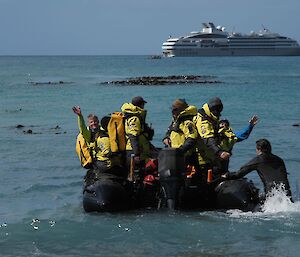 People in an inflatable boat heading for a cruise ship