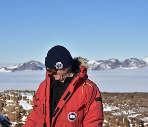 A man in a beanie and red jacket is smiling to himself