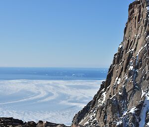 The sea is seen in the distance from a mountain rising above an ice plateau