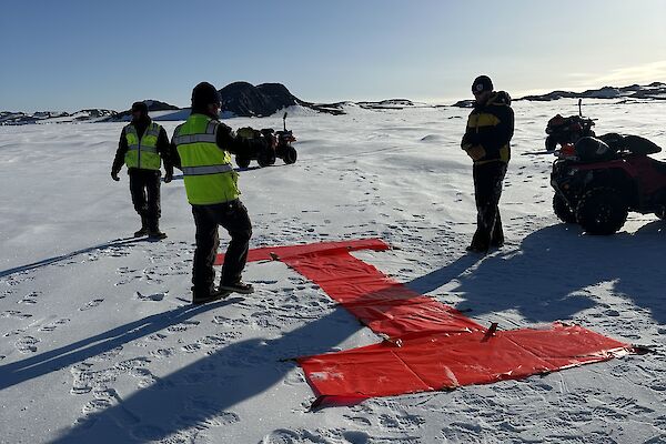 People are placing a big red letter "I" in the snow with plastic panel markers