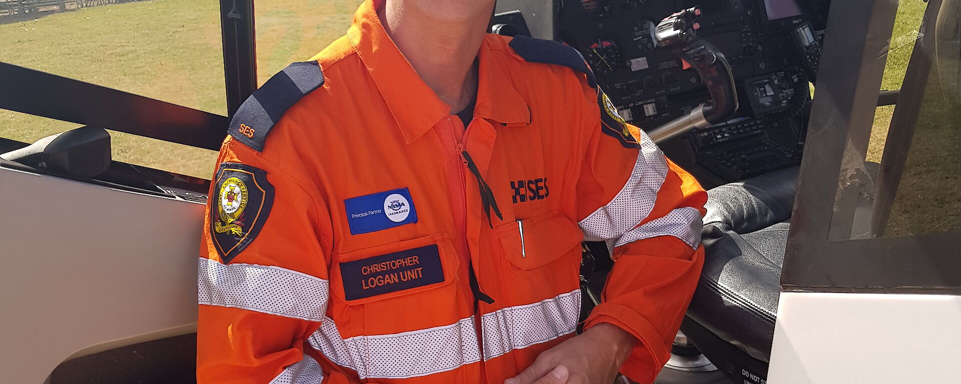 A smiling man in an SES uniform stands by the open pilot's door of a helicopter