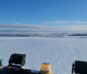 Icebergs and islands can be seen in the distance from atop a vehicle on an ice plateau