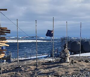 An Australian flag is at half mast with the sea in thee background