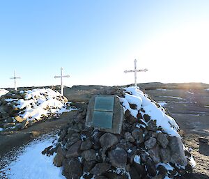 Three gravesites lay snow covered on a rocky hill