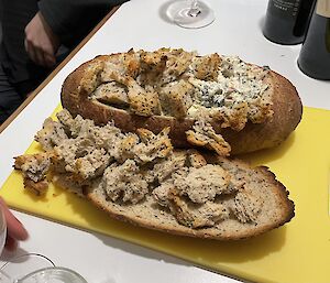 A cob-loaf is on a cutting board upon a table
