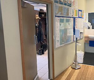 A partially opened interior door leading from the station's cold porch to the internal mess. The beige door is a normal thickness door.