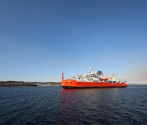 A large icebreaker approaches a port in calm waters