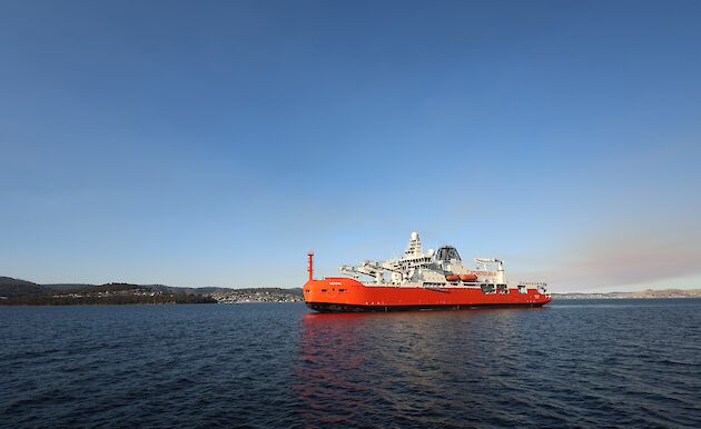 A large icebreaker approaches a port in calm waters