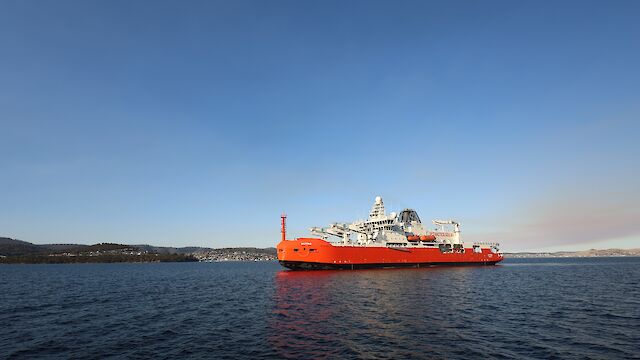 A large icebreaker approaches a port in calm waters