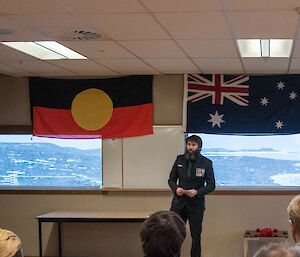 A man wearing medals delivers addresses an Anzac Day ceremony inside Davis research station