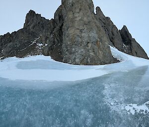 A frozen lake with a rocky peak rising in the background
