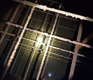 This photo shows some very old thin tie-in bars, criss-crossed inside the old water tank. They are illuminated by work light and encrusted with rust.