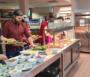 People are collecting dinner from a Bain-marie