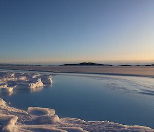 Sea ice is forming across the water with islands in the distance