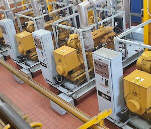 This photo is the inside of a machinery room. There are four identical yellow and grey generators that provide power to our station.