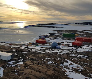 Station buildings lay on a rocky landscape with an ice covered sea in the background