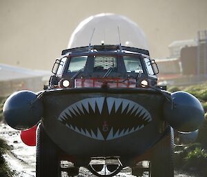 A large amphibious vehicle drives down a wet road.