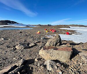 Red and yellow huts and tents in a rock and ice landscape