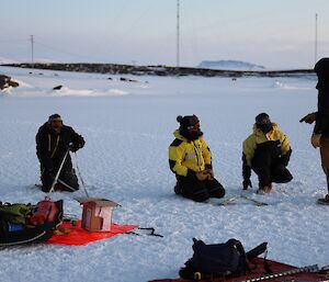 Four men are on an iced over harbour conducting training with ice anchors