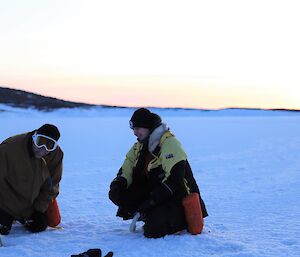 A man and woman are on an iced over harbour practicing the use of ice anchors