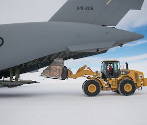 A tractor removes a pallet of cargo from the back of a C17 Globemaster.