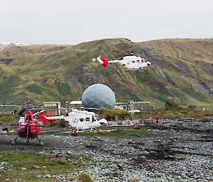 Three helicopters can seen on a hilly green island