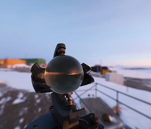 A sunset is reflected in a glass ball with brightly coloured buildings in the background