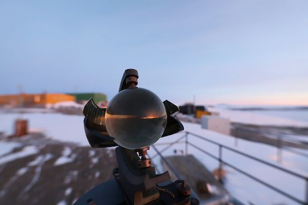 A sunset is reflected in a glass ball with brightly coloured buildings in the background