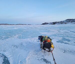 A sled fully laden with bags and equipment sitting on the sea-ice.