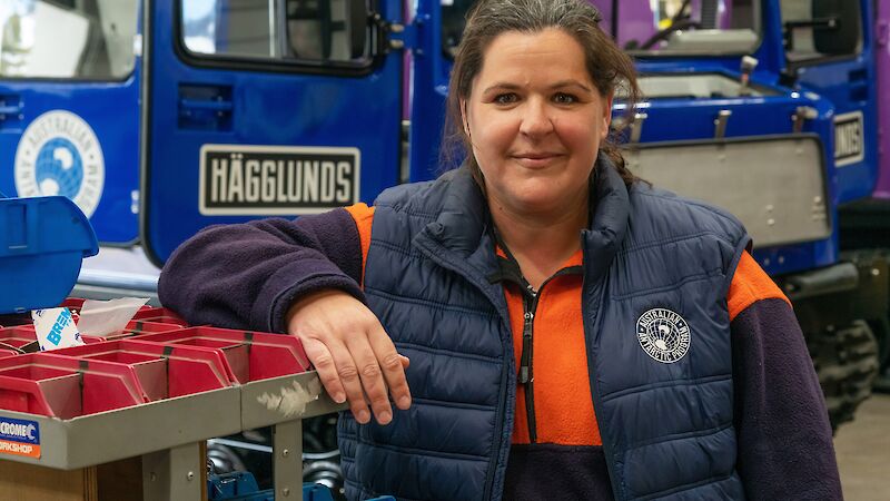 A woman standing in front of a blue hagglunds vehicle