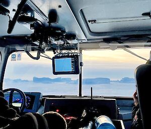 A view from the backseat of a Hägglunds looking through the front window of the vehicle. There are icebergs in the frozen sea-ice.