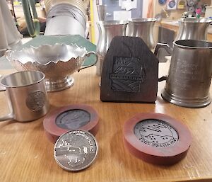 A number of pewter objects are behind two silicon moulds on a wooden table.