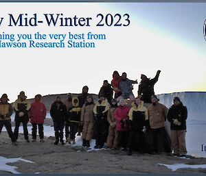 A greeting card wishing a happy mid-winter features a group of nineteen people on a rocky landscape with icebergs in the background