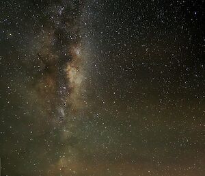 The Milky Way galaxy is visible in the night sky with a red and green, faint Aurora in the lower half of the frame.