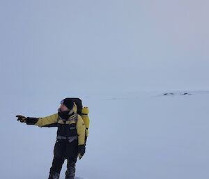 The author in her yellow survival clothes with a little bit of horizon visible in the background but an otherwise seamless white background of snow and cloud.